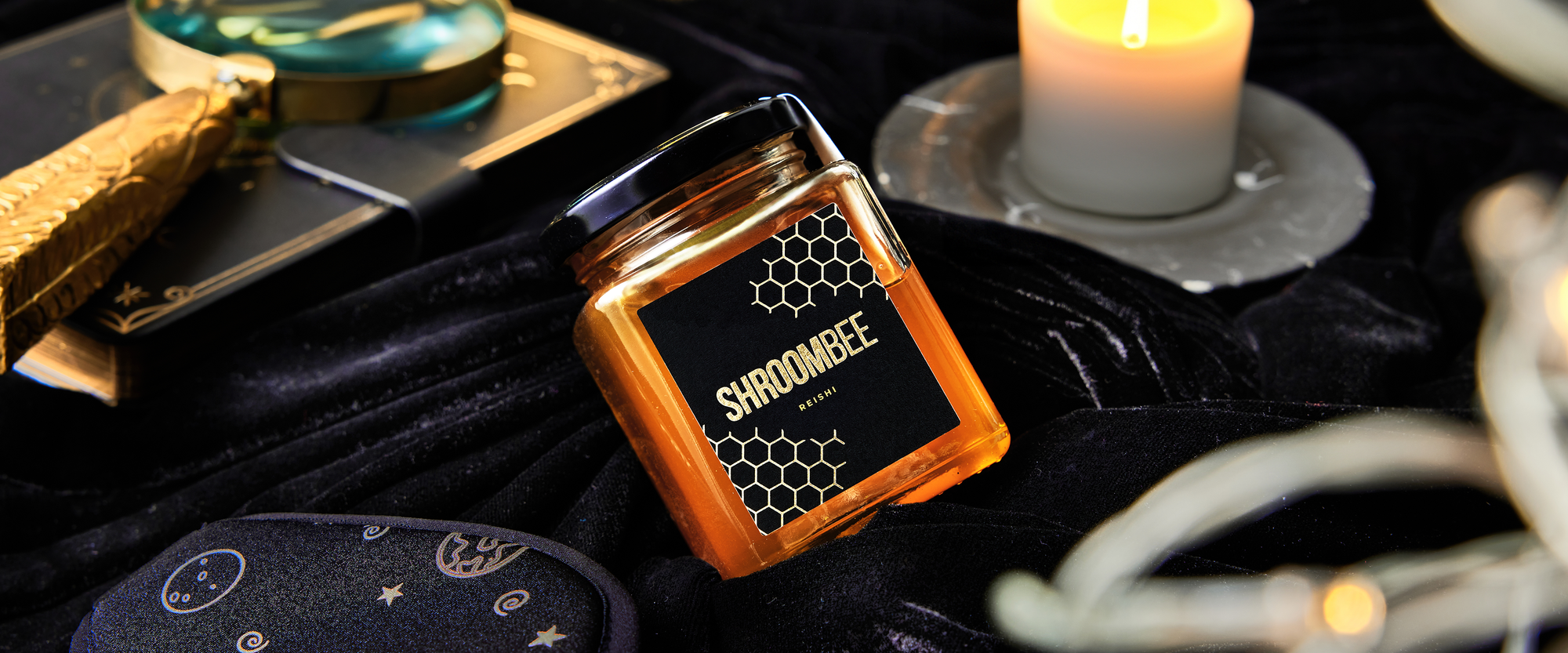Jar of Shroombee on a dark surface with candles and other items.