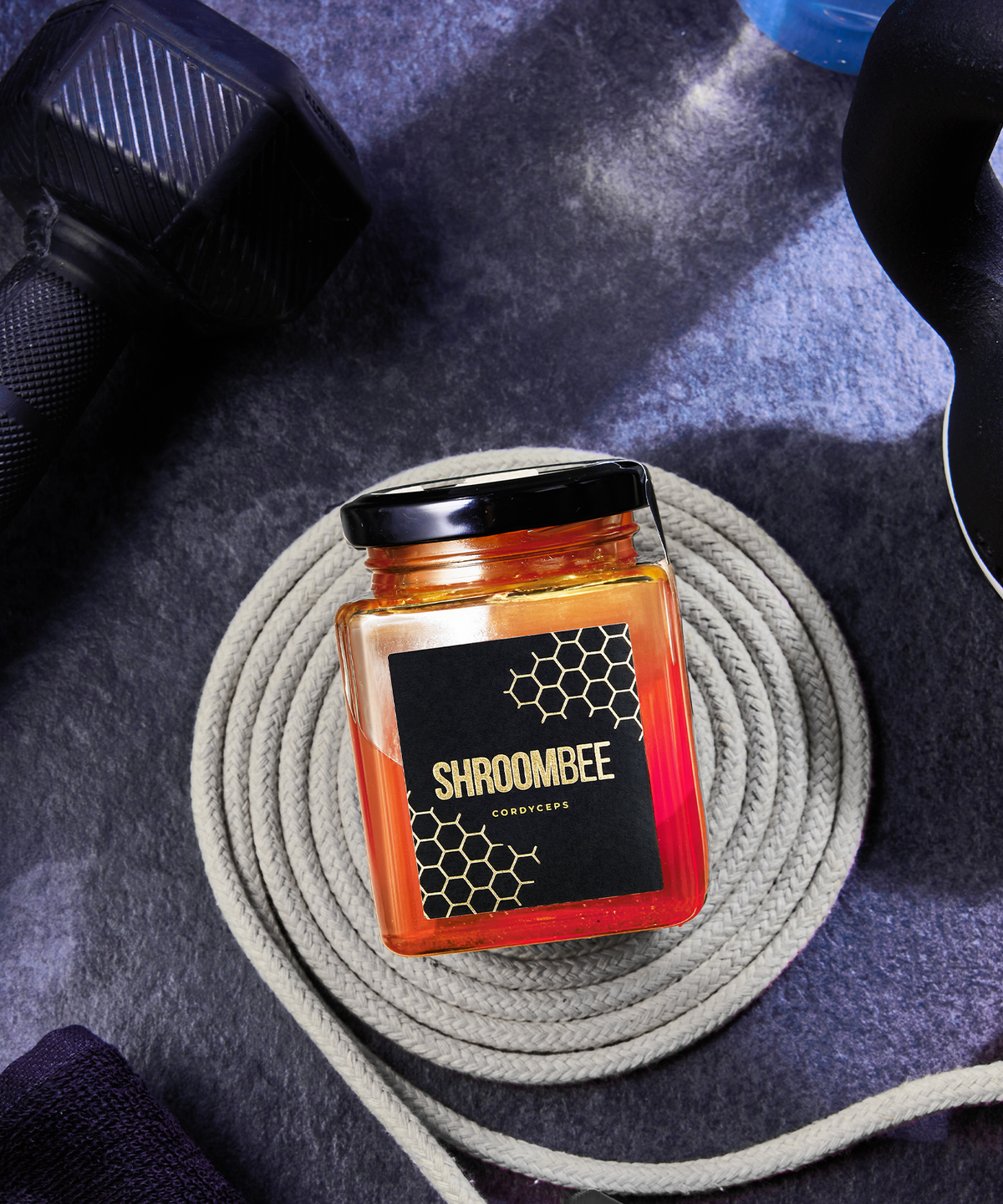 Jar of Shroombee product on a textured surface with gym equipment in the background