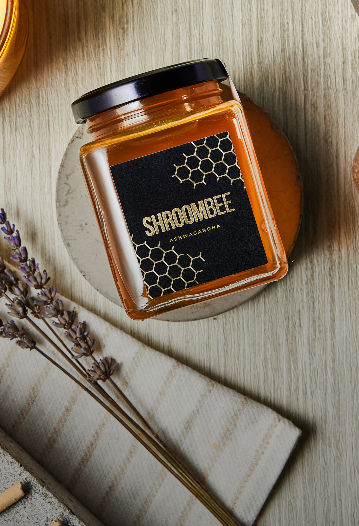 Jar of honey with 'Shroombee' label on a wooden surface with lavender.