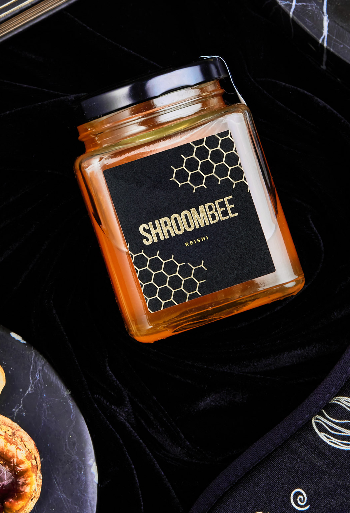 Jar of honey with 'Shroombee' label on a dark surface